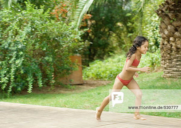 Girl in bathing suit running in back yard