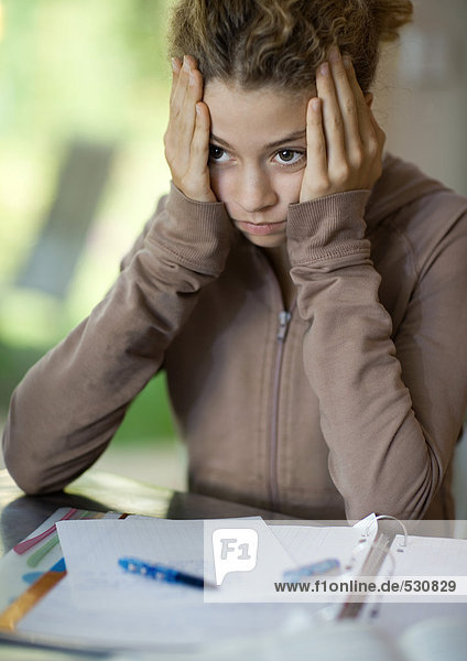 Preteen girl doing homework  holding head