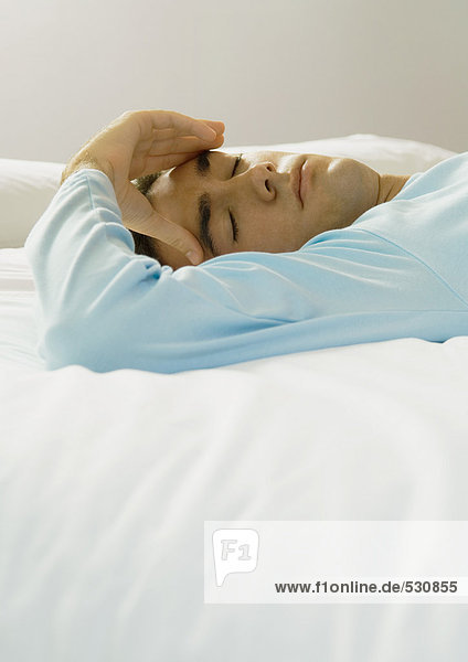 Man lying in bed  holding head