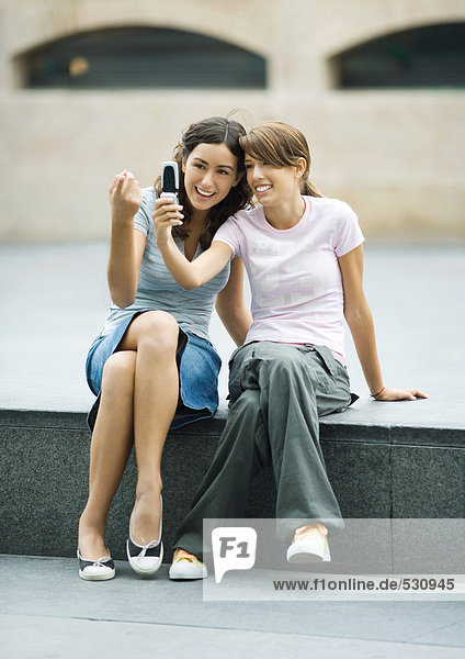 Teenagermädchen fotografieren zusammen mit dem Handy