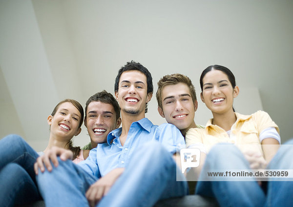 Group of teens sitting side by side  smiling at camera  low angle view