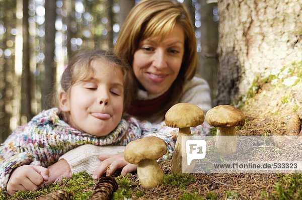 Mutter und Tochter beobachten Steinpilze im Wald
