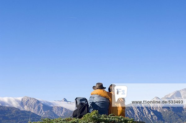 Paar in den Bergen sitzend  Blick auf die Aussicht  Rückansicht