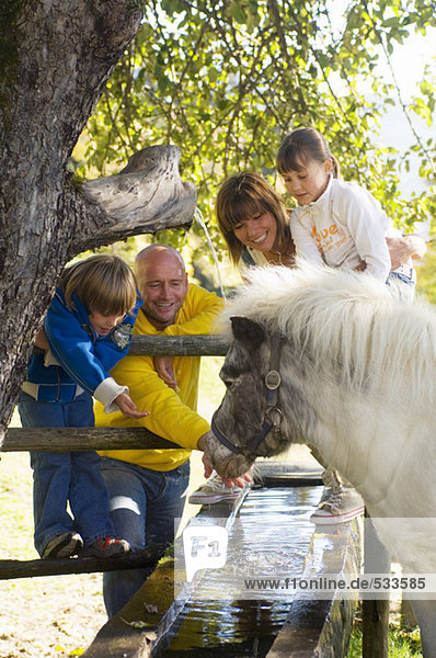 Familie beobachtet Pony am Brunnen