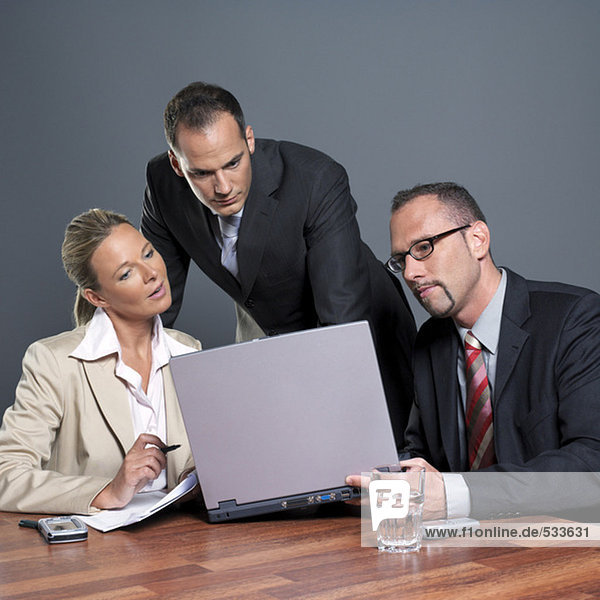 Business people looking at laptop at conference table