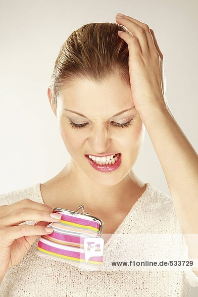 Junge Frau hält Geldbörse  Zähne zusammenbeißen  Nahaufnahme