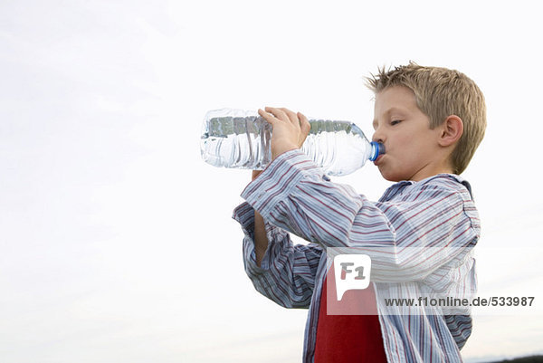 Junge (10-12) trinkt aus der Wasserflasche  Seitenansicht