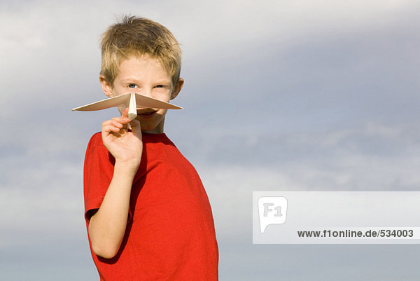 Junge (10-12) hält Papierflugzeug