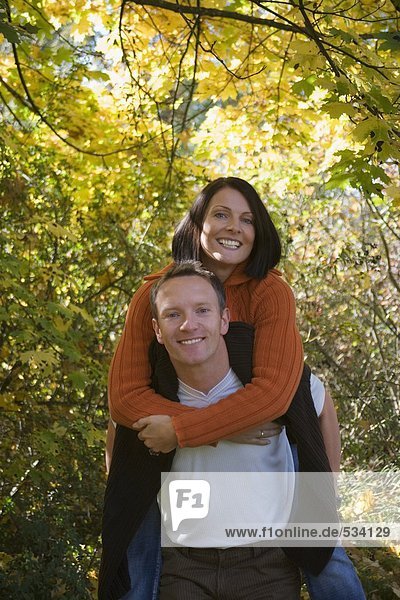 Man carrying woman piggyback  smiling  portrait