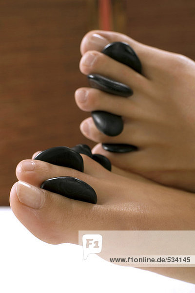 Woman receiving hot stone massage on feet  close-up