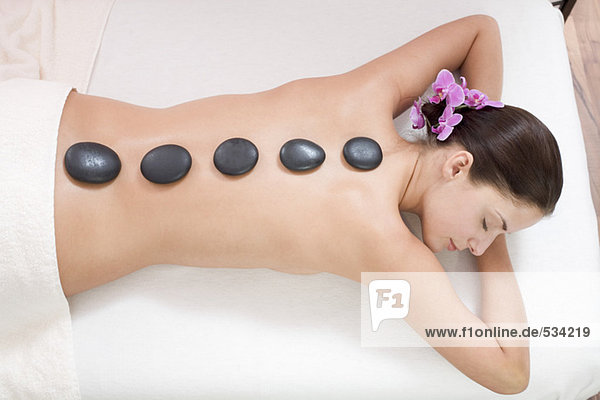 Junge Frau erhält Hot-Stone-Massage  erhöhte Ansicht