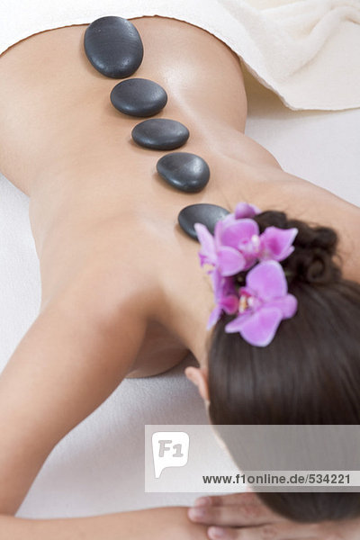 Junge Frau erhält Hot-Stone-Massage  Rückansicht