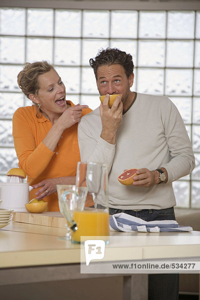 Mature couple in kitchen  Man eating grapefruit