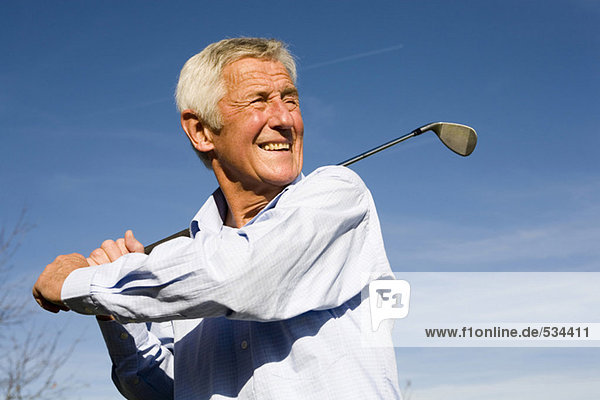 Senior Mann schwingt Golfschläger  lächelnd  Nahaufnahme