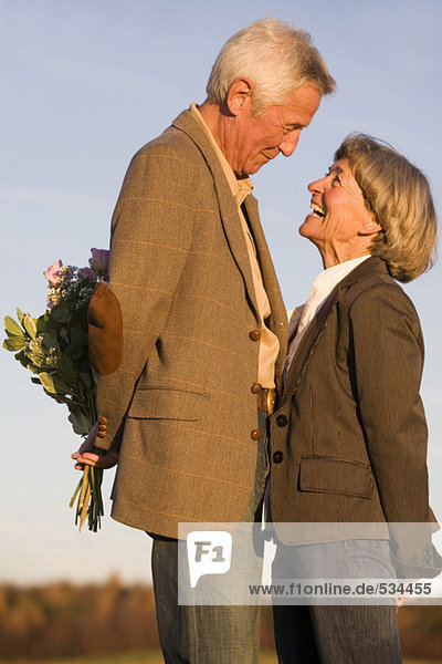 Senior Paar  Mann versteckt Blumenstrauß  Seitenansicht