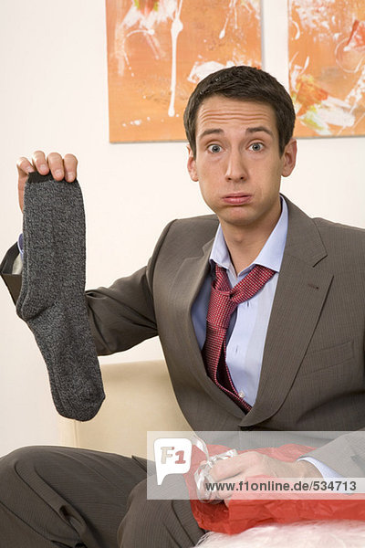 Man sitting on sofa  holding socks  portrait  close-up