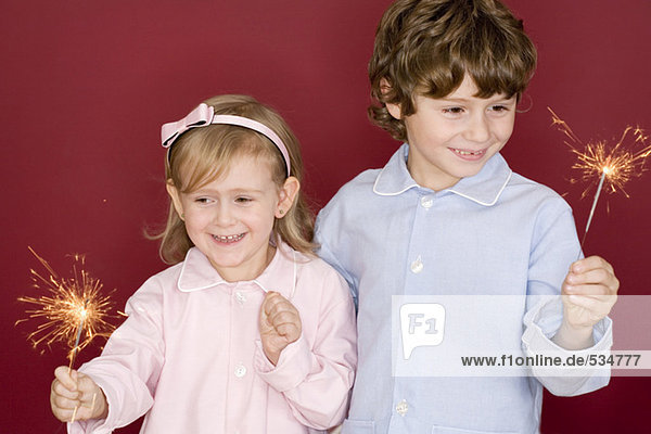 Junge (4-7) und Mädchen (3-4) halten Wunderkerzen  lächelnd