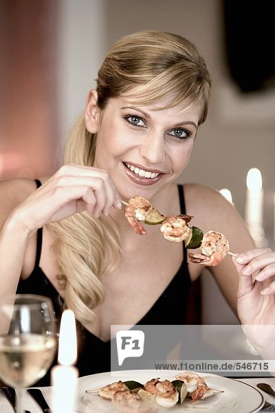 Young woman eating a shrimp kebab