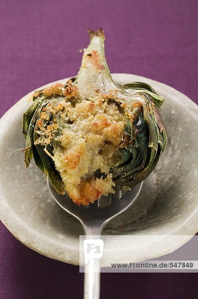 Stuffed artichoke with gratin topping on spoon