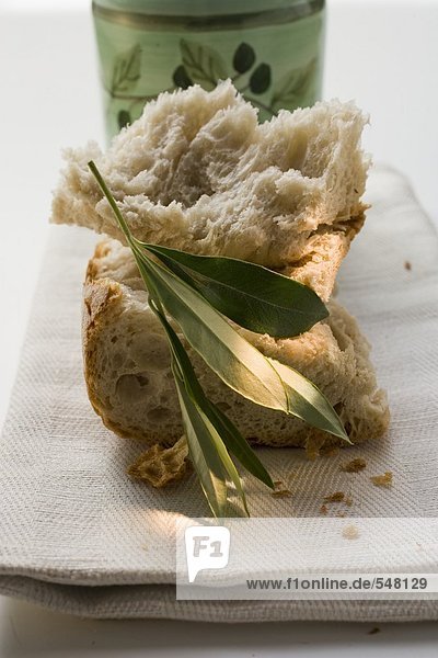 Weissbrotstücke auf Leinentuch mit Olivenzweig
