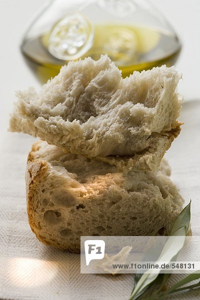 Weissbrotstücke auf Leinentuch mit Olivenzweig  Olivenöl