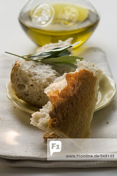 Weissbrotstücke auf Teller mit Olivenzweig  Olivenöl