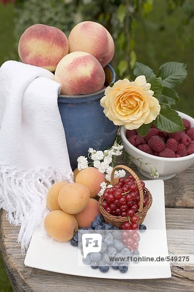 Pfirsiche  Aprikosen und Beeren auf Tisch im Garten