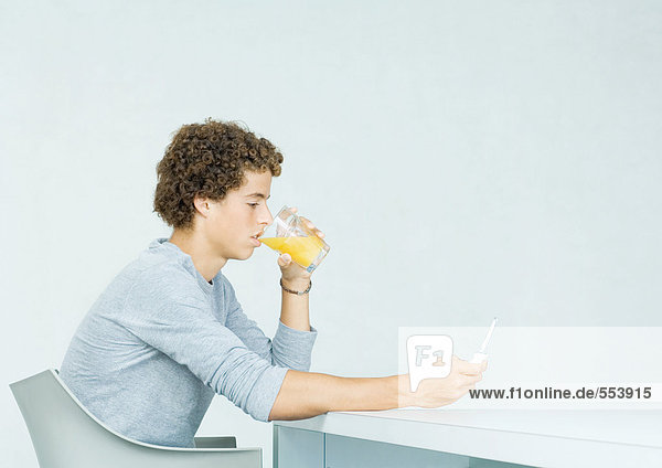 Teenager-Junge mit Handy  Saft trinken