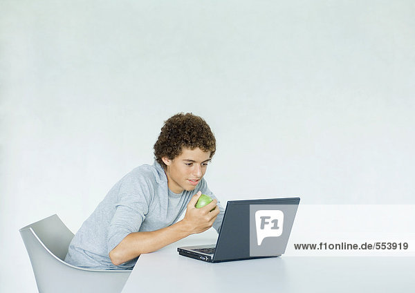 Teenager-Junge mit Laptop und Essapfel
