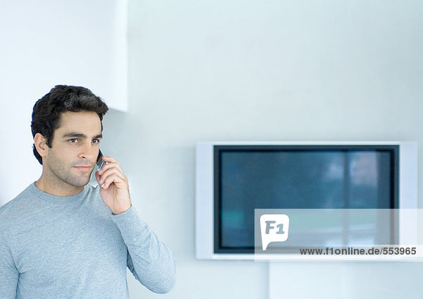 Mann mit Telefon  Widescreen-TV im Hintergrund