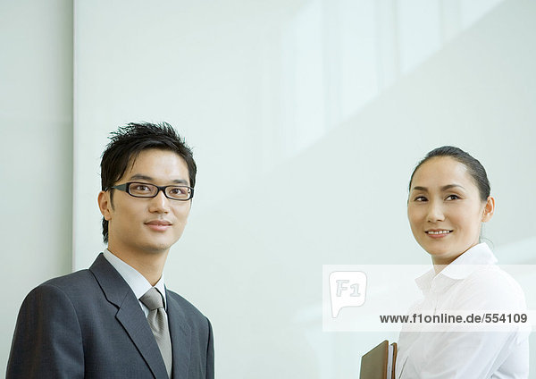 Businessman and businesswoman looking away  smiling  head and shoulders