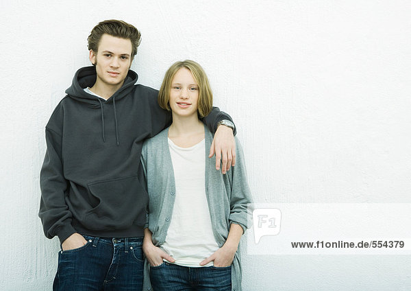 Young couple leaning against wall  looking at camera  portrait