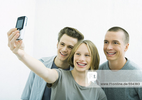 Three young friends taking photo together with cell phone
