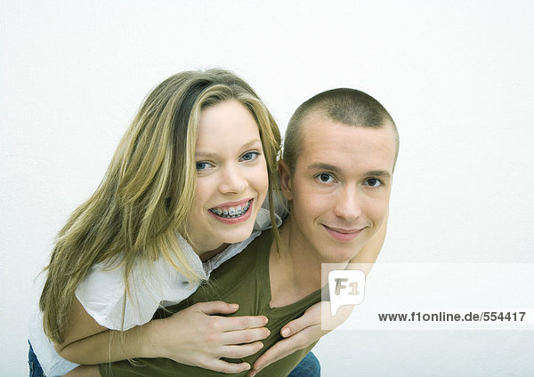 Junges Paar  Teenagermädchen auf dem Rücken eines jungen Mannes  weißer Hintergrund