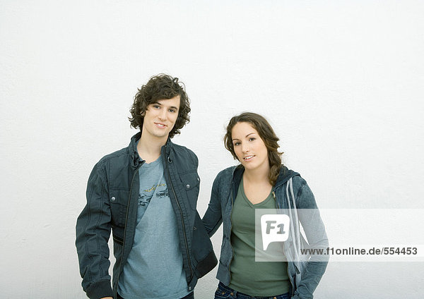 Junges Paar steht nebeneinander  schaut in die Kamera  Portrait  weißer Hintergrund