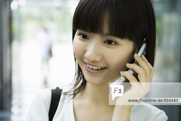 Young woman using cell phone  smiling