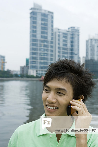 Junger Mann mit Handy am Fluss