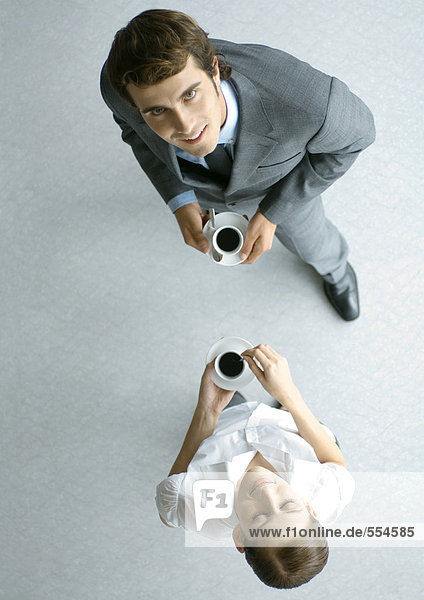 Male and female associates having coffee  full length  high angle view