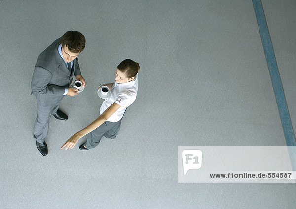 Male and female associates having coffee  woman pointing  full length  high angle view