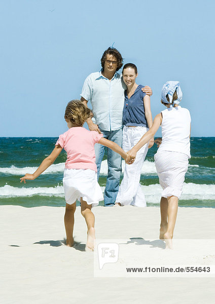Familie am Strand  zwei Mädchen gehen Hand in Hand zu den Eltern