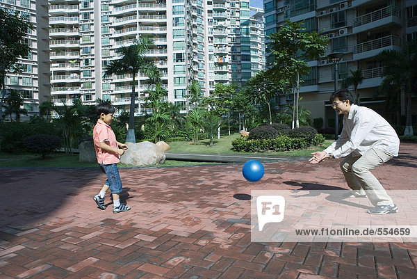 Father and son playing ball in apartment complex