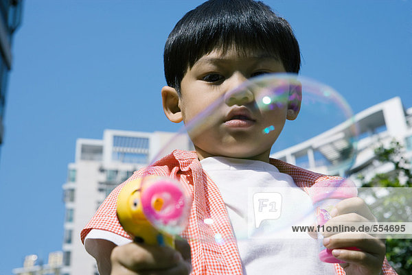 Junge macht Blasen mit Blasenpistole