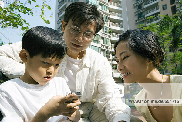 Family  boy using cell phone while parents watch