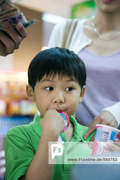 Boy eating sweet snack at checkout counter