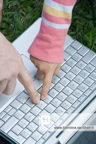 Kinder- und Erwachsenenhände durch Tastendruck auf der Tastatur