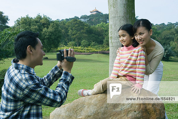 Mann filmt Frau und Tochter im Park mit Videokamera