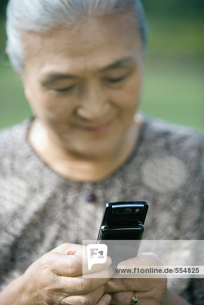 Seniorenfrau wählt Handy