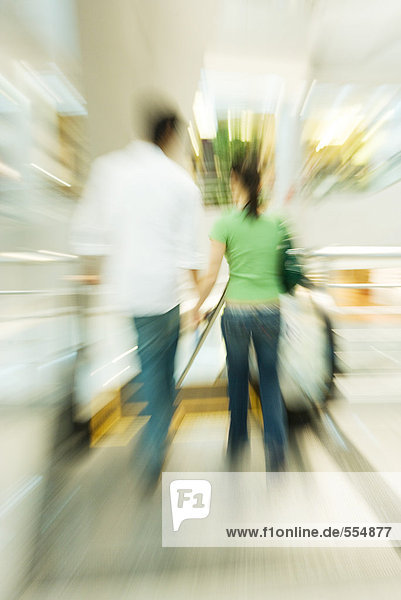 Couple walking toward escalator  blurred motion