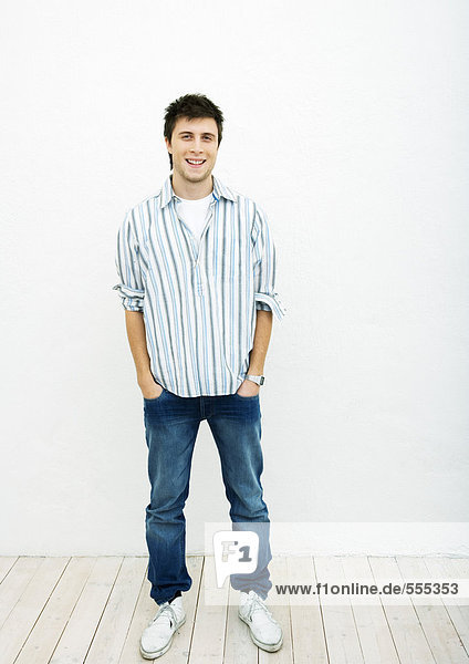 Young man standing with hands in pockets  full length portrait