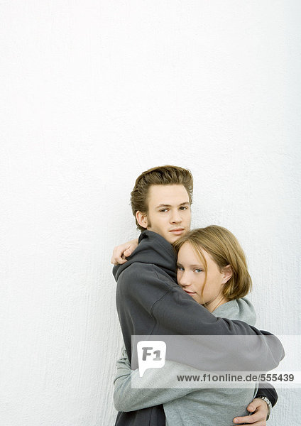 Junger Mann und Frau  die sich umarmen und in die Kamera schauen.